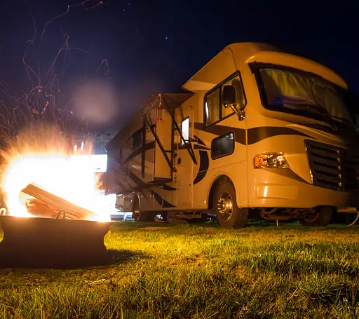 RV parked in a jungle near bonfire